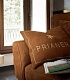 Брендированые подушки на коричневом диване Glamour